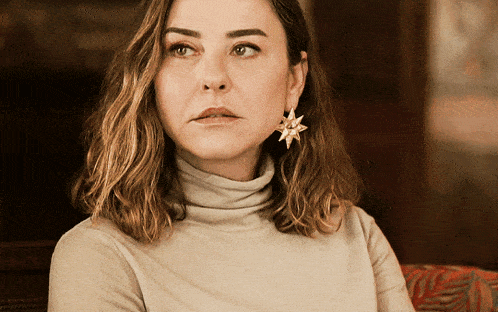 a woman wearing a turtleneck sweater and earrings with a star on them