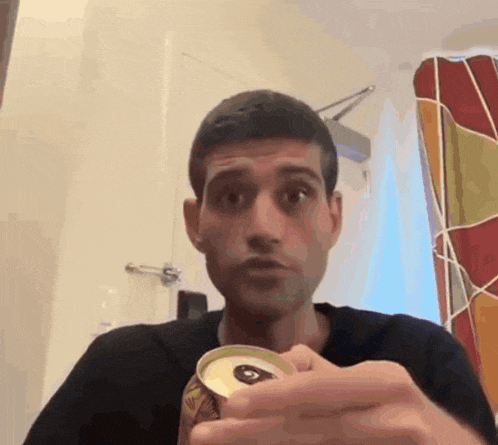 a man in a black shirt is holding a can of something