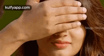 a woman is covering her face with her hand and smiling .