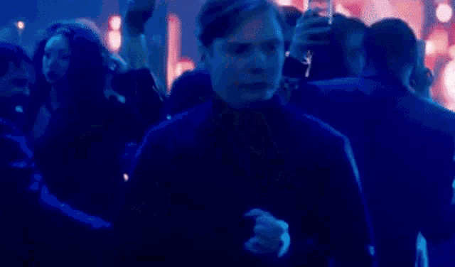 a man is standing in a crowd of people at a party in a dark room .