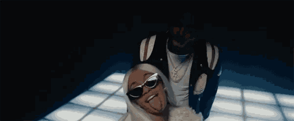 a man and a woman are making funny faces in a dark room . the woman is wearing sunglasses .