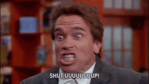 a man in a suit and tie is making a funny face and saying `` shut uuuuuuup '' .
