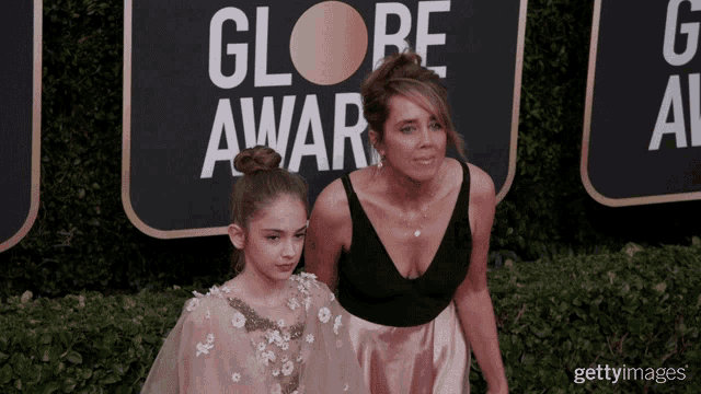 two women on a red carpet in front of a sign that says globe awards