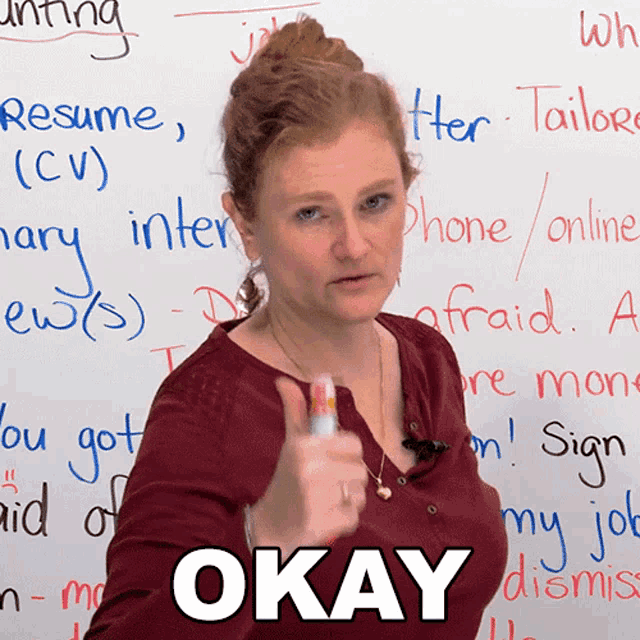 a woman is giving a thumbs up in front of a whiteboard that says okay