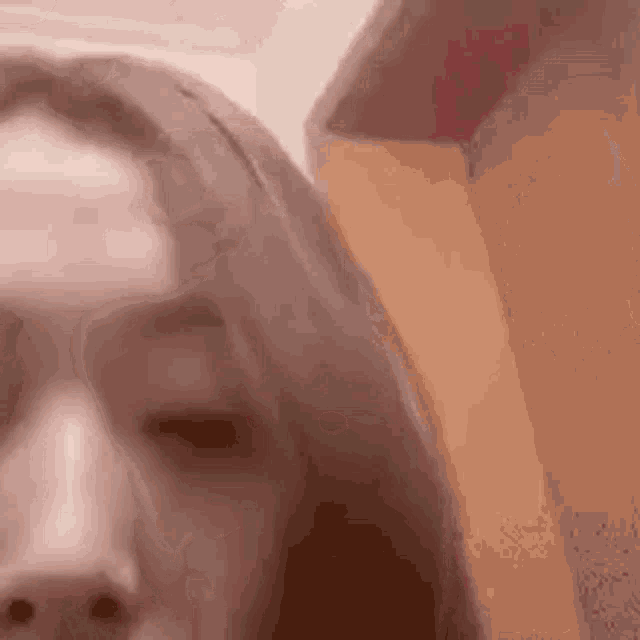 a close up of a woman 's face with her eyes closed and a blurred background .