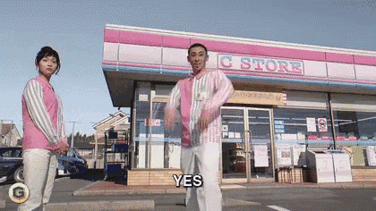 a man and a woman are dancing in front of a store that says yes