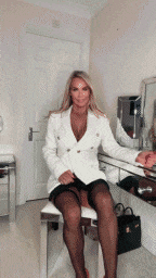 a woman in a white jacket is sitting on a chair in front of a mirror