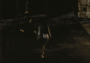 a group of people are walking down a dark street