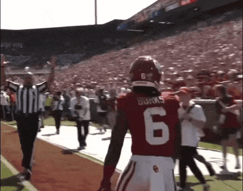 a football player wearing a number 6 jersey walks off the field