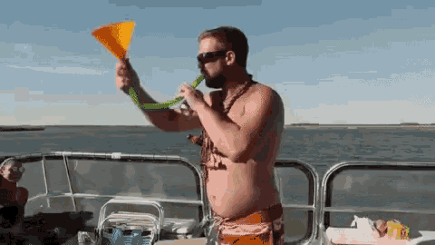 a shirtless man is blowing a horn on a boat in the water