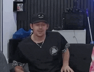 a man wearing a hat and a necklace is sitting on a couch in a living room .