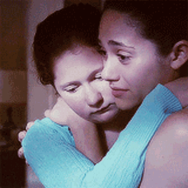 two women are hugging each other and one is wearing a blue sweater
