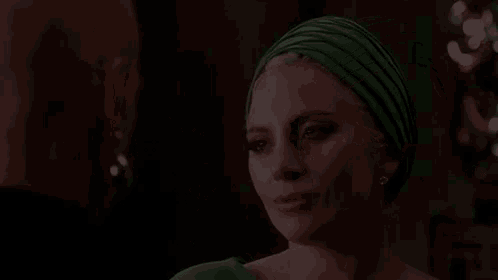 a woman in a green turban is looking at another woman in a black dress .