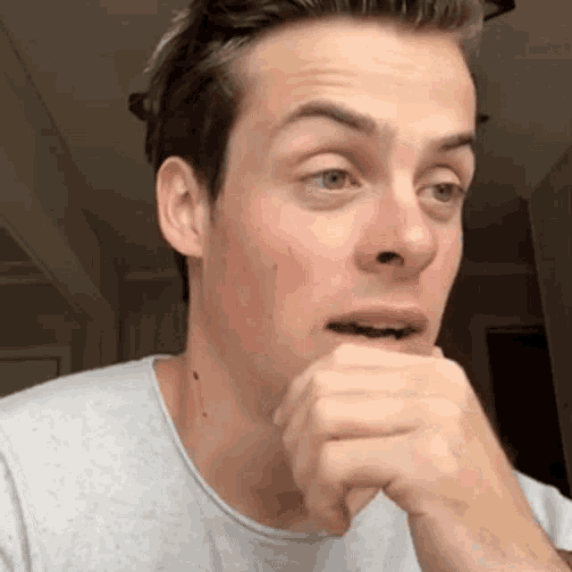 a man covering his mouth with his hand and looking at the camera