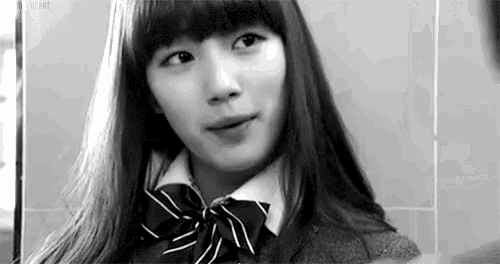 a black and white photo of a young woman wearing a school uniform and a bow tie .