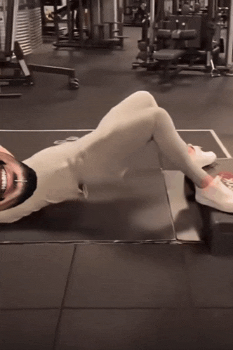 a man is laying on the floor in a gym with his head on a box