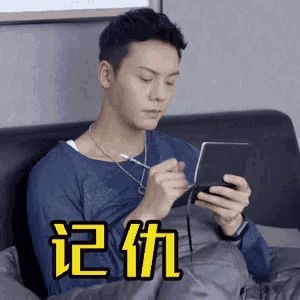 a man is sitting on a couch holding a cell phone and wearing headphones .
