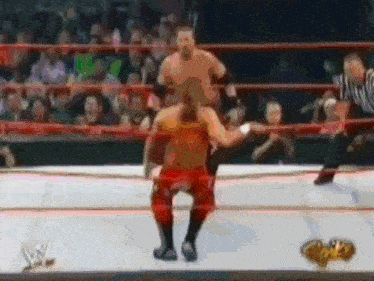 two wrestlers are fighting in a wrestling ring with a w logo in the background