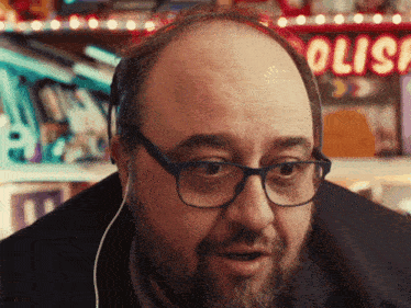 a bald man with glasses and a beard stands in front of a sign that says polis