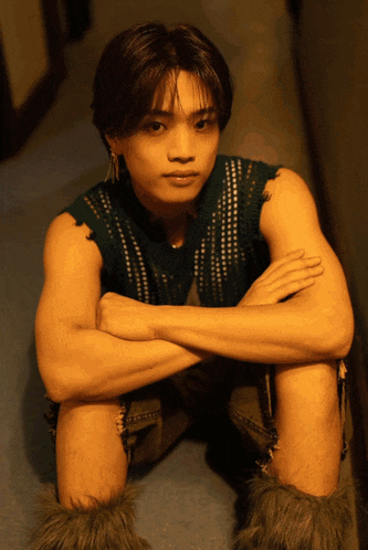 a young man sitting with his arms crossed wearing furry boots