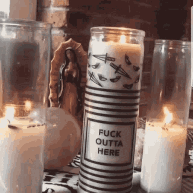 a candle that says fuck outta here is surrounded by other candles .