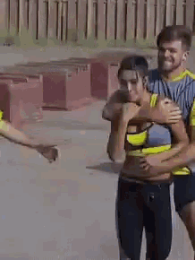 a man is carrying a woman in his arms while they are walking down the street .