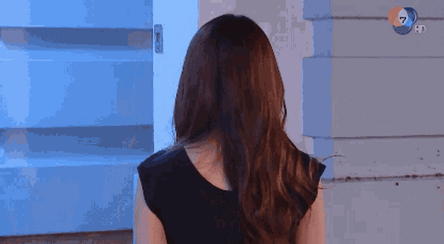 a woman in a black dress is standing in front of a blue door ..