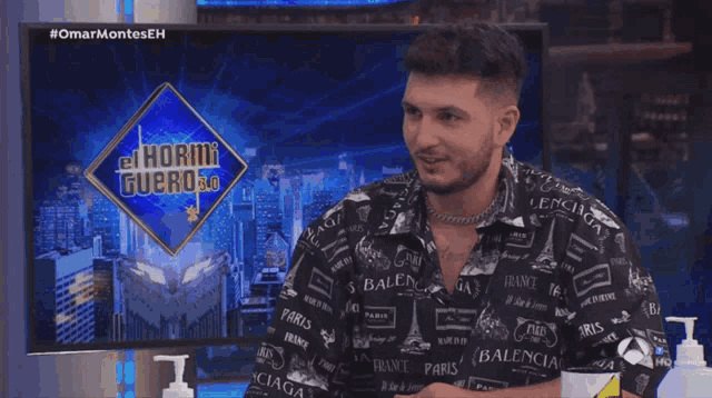 a man sitting in front of a sign that says el hormiguero on it