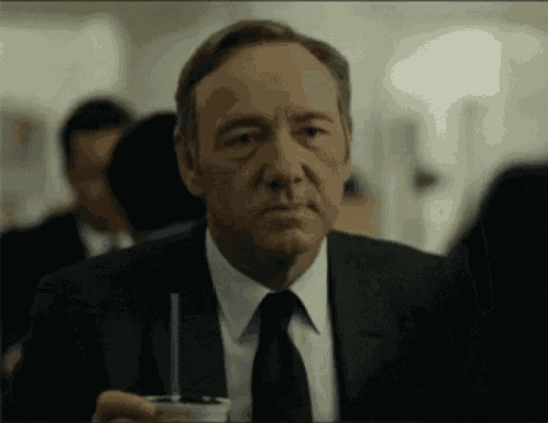 a man in a suit and tie is holding a cup with a straw in his hand .