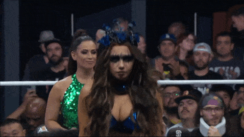 two women are standing in front of a crowd with the letter s on their neck