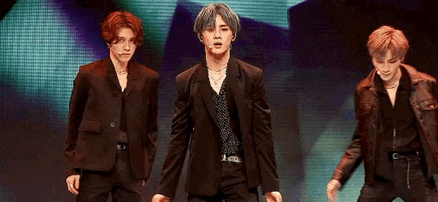a group of young men are standing next to each other on a stage holding hands and dancing .