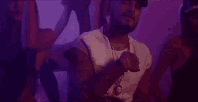 a man is singing into a microphone while standing in front of a group of women .