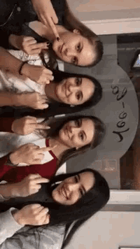 four girls are posing for a picture in front of a sign that says ' noo ' on it