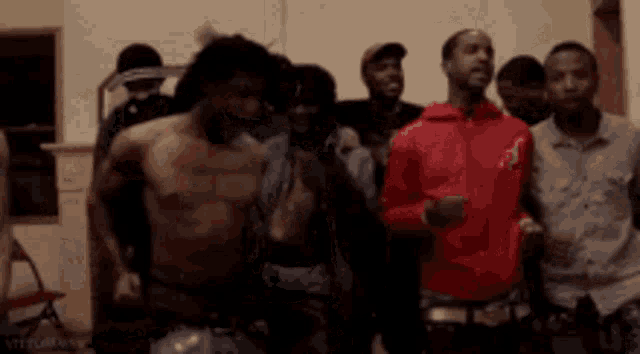 a group of men are standing in a room without shirts on