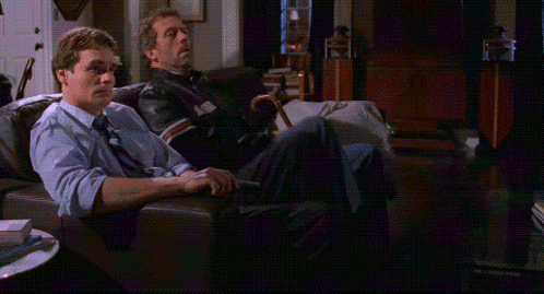 two men sitting on a couch with their feet up