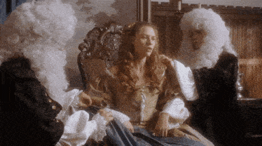 a woman is sitting in a chair with two men in white wigs