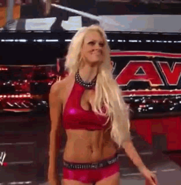 a woman in a pink top and pink shorts is standing in front of a sign that says a v .