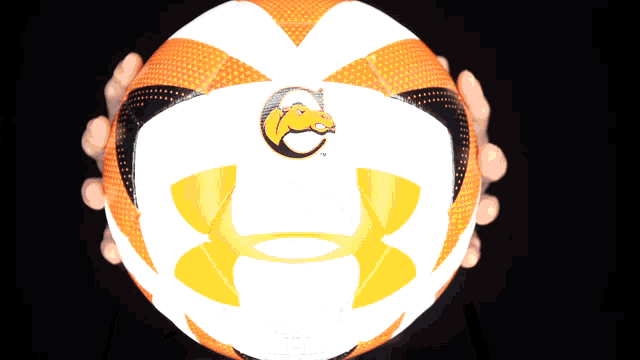 a person holding an orange and white under armour basketball