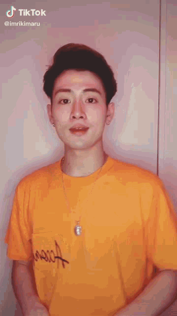 a man in an orange shirt is making a funny face while wearing a tiktok account