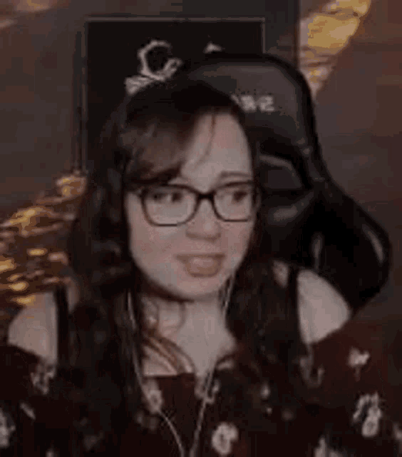 a woman is wearing glasses and headphones while sitting in a gaming chair .