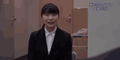 a woman in a suit and white shirt is sitting in a chair and looking at the camera .