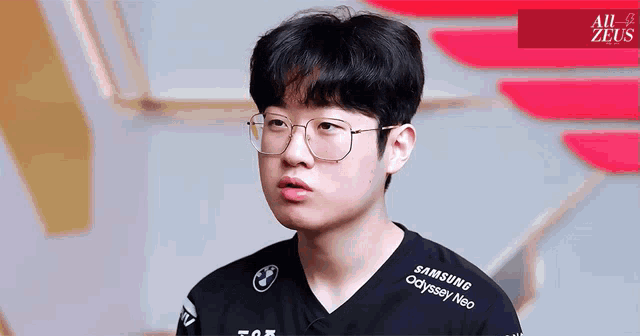 a young man wearing glasses and a black samsung odyssey neo shirt
