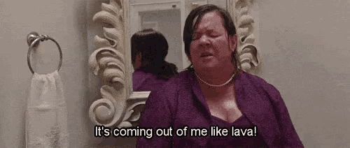 a woman in a purple dress is sitting in front of a mirror in a bathroom and crying .