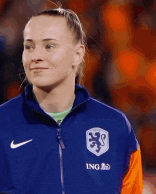 a woman wearing a blue nike jacket with ing written on it
