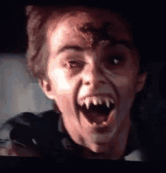 a close up of a person 's face with fangs and a spider on his face .