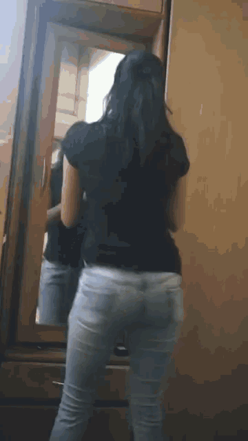 a woman standing in front of a mirror looking at herself
