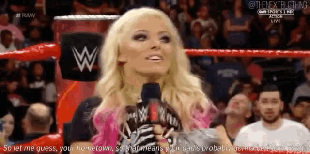 a woman is talking into a microphone in a wrestling ring