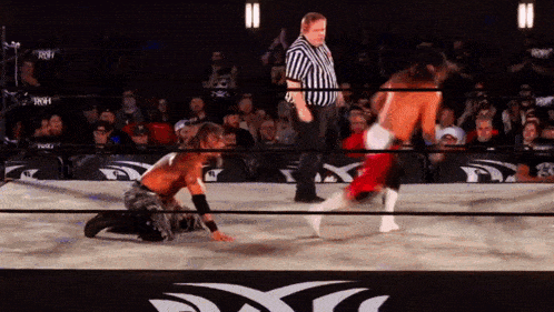 a wrestler is kneeling down in front of a referee in a ring with a x on it