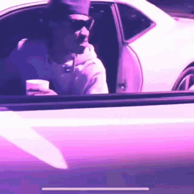 a man is sitting in the driver 's seat of a white car .