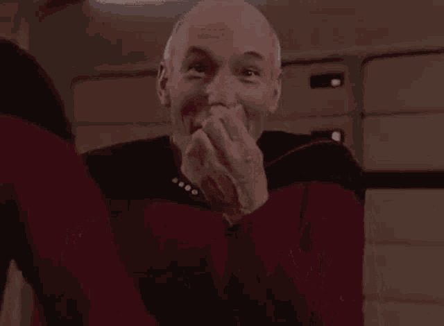 a man is laughing with his hands over his mouth .